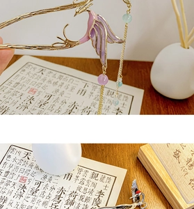 Detail of golden phoenix hairpin with purple enamel wings and long hanging tassels