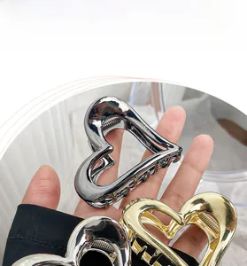 Detail showing hand holding gold and silver hollow heart metal hair claws set