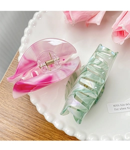Detail of pink and green marbled half-round claw clips on a white ceramic plate