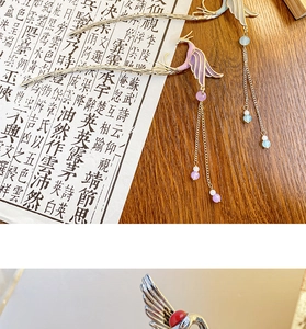 Detail of golden phoenix hairpin with lilac enamel wings and dangling beaded tassels