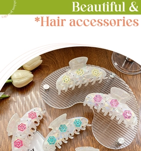 Detail view of pearlized acrylic hair claws with colorful 3D floral accents and rhinestones