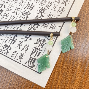 Elegant Chinese vintage green leaf and bead earrings showcased on dark wooden hairpins