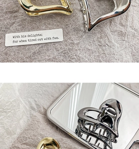 Detail of hollow heart metal hair claws in gold and silver finishes with polished texture