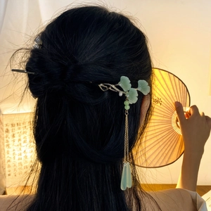 Traditional Chinese bird hair pin with green leaves and long tassel on a half-up bun