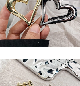 Detail of hollow heart metal hair claws in polished gold and silver metallic finishes