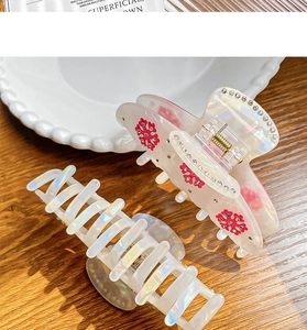 Detail of large iridescent snowflake hair claws with pink floral pattern on wood background