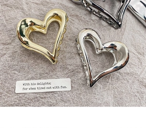 Detail of hollow heart-shaped metal hair claws in polished gold and silver finishes