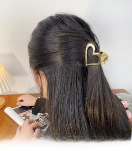 Detail of hollow heart-shaped metal hair claw clips in gold and silver finish on a woman