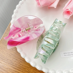 Pink marble and green pearlescent acetate hair claws in a decorative white plate