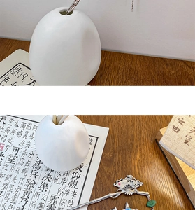 Detailed view of silver fan hair pin with green beads on a wooden desk background