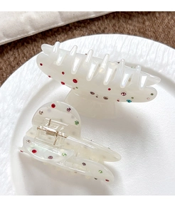 Détail de pinces à cheveux en acétate nacré avec strass colorés sur une assiette