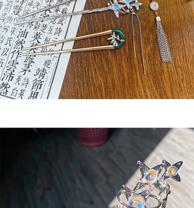 Detail view of silver planet hairpin with blue stone tassel and gold bamboo U-shaped fork
