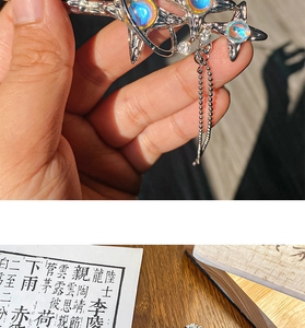 Detailed view of silver starburst hair stick with iridescent stones and tassels