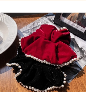 Detail of velvet pearl scrunchies in red and black showing texture and luster