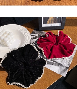 Detail view of large velvet scrunchies with white pearls in black and burgundy red colors