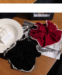 Close-up of luxury velvet scrunchies in black and burgundy with elegant pearl edge details