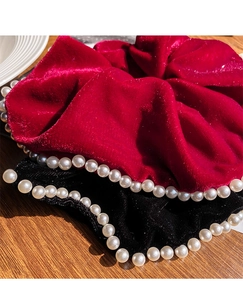 Detail of luxury velvet scrunchies in wine red and black with elegant pearl trim