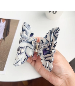 Gros plan sur la pince à cheveux papillon avec motif floral marbré en violet et blanc
