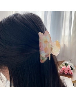Détail d'une pince à cheveux papillon avec texture marbrée colorée sur cheveux coiffés