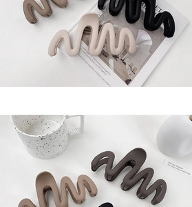 Macro detail of large wavy matte hair claws in neutral colors for thick hair