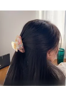 Gros plan d'une pince à cheveux élégante en acétate marbré portée sur un chignon flou