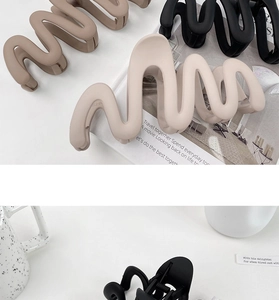 Detail of matte wavy shark hair clips in black, beige, and brown on a white background