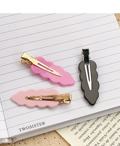 Close-up of three acrylic traceless hair clips in pink and black with wavy edges