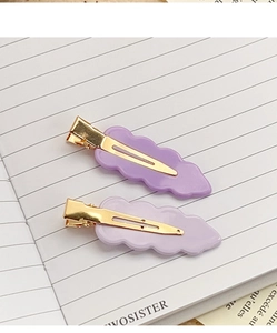 Close-up of two purple wavy acrylic hair clips with golden metal duckbill bases