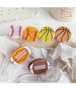 Détail de mini-pinces à cheveux en acétate avec des motifs de basket et de football