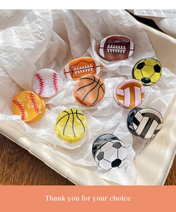 Détail de pinces à cheveux en acétate avec motifs de ballons de basket et football