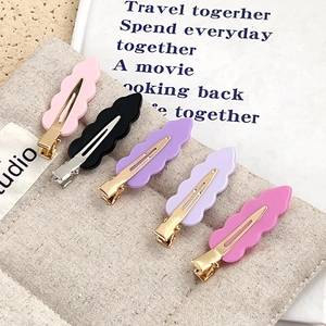 5-piece set of matte acrylic wave hair clips in assorted colors on a beige canvas surface