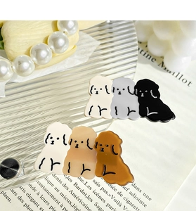 Detail von Cartoon-Hundehaarklammern in Beige und Braun auf dekorativem Glastablett