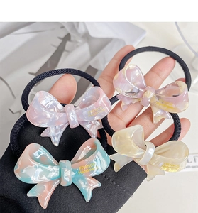 Detail of four acetate bow hair ties with marble texture and handmade gold lettering
