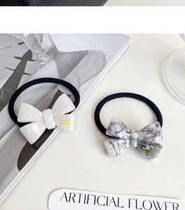 Close-up of handmade cream and marble acetate bow hair ties on elegant magazine prop
