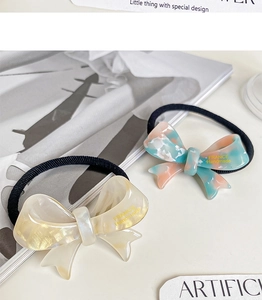 Detailed macro view of acetate bow hair ties in marble blue and pearlescent beige colors
