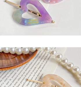 Detail view of heart-shaped marble acetate hair clips and white pearl accessory