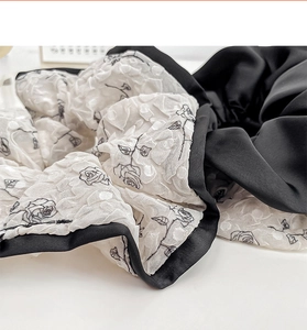 Detail of floral scrunchie with 3D embossed rose pattern and black satin edge trim