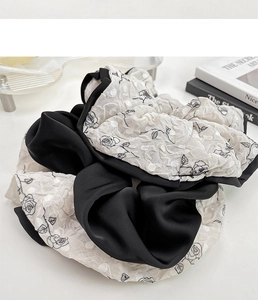 Detailed view of oversized scrunchie with black rose pattern and satin jacquard fabric