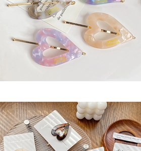 Detail of vintage heart-shaped acetate hair pins with marble texture and gold metal rods