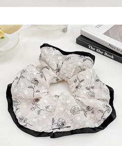 Detailed view of floral scrunchie with black rose print and elegant satin contrast piping