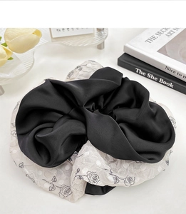 Detail of elegant black satin and white floral rose pattern organza scrunchie