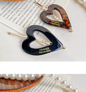 Detail view of heart-shaped acetate hair clips with France handmade logo on vintage props