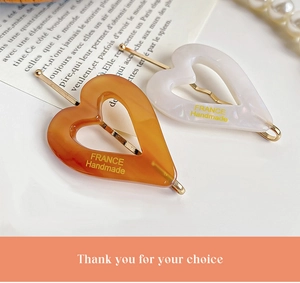 Detailed macro of amber and cream acetate heart hair clips with golden France lettering