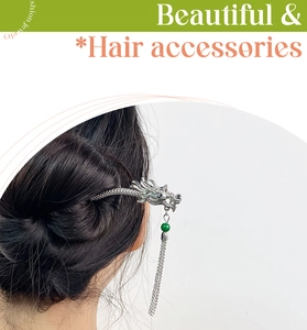Detail of silver dragon hair pin with green bead and metallic tassels in hair