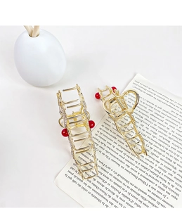 Close-up of golden dragon hair claws with rhinestones and red beads for elegant styling