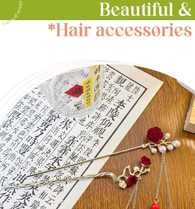 Detailed close-up of golden hair pin with red roses, pearls and long tassels in vintage style