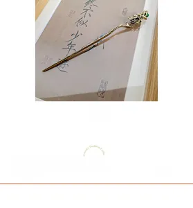 Detail of golden dragon hair stick with intricate carving and a green bead accent