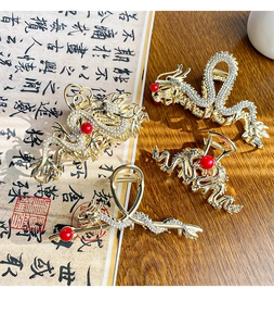 Macro detail of four gold dragon hair claws with rhinestones and red pearls in Chinese style