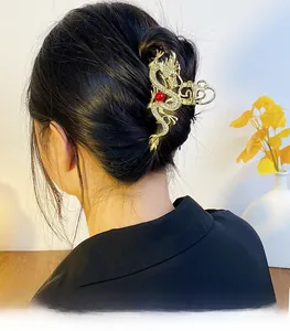 Detail of a golden dragon hair claw clip with rhinestones worn by a model in a cozy setting