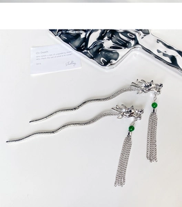 Detail of silver dragon hair pin with metallic fluid curves and green beaded tassels
